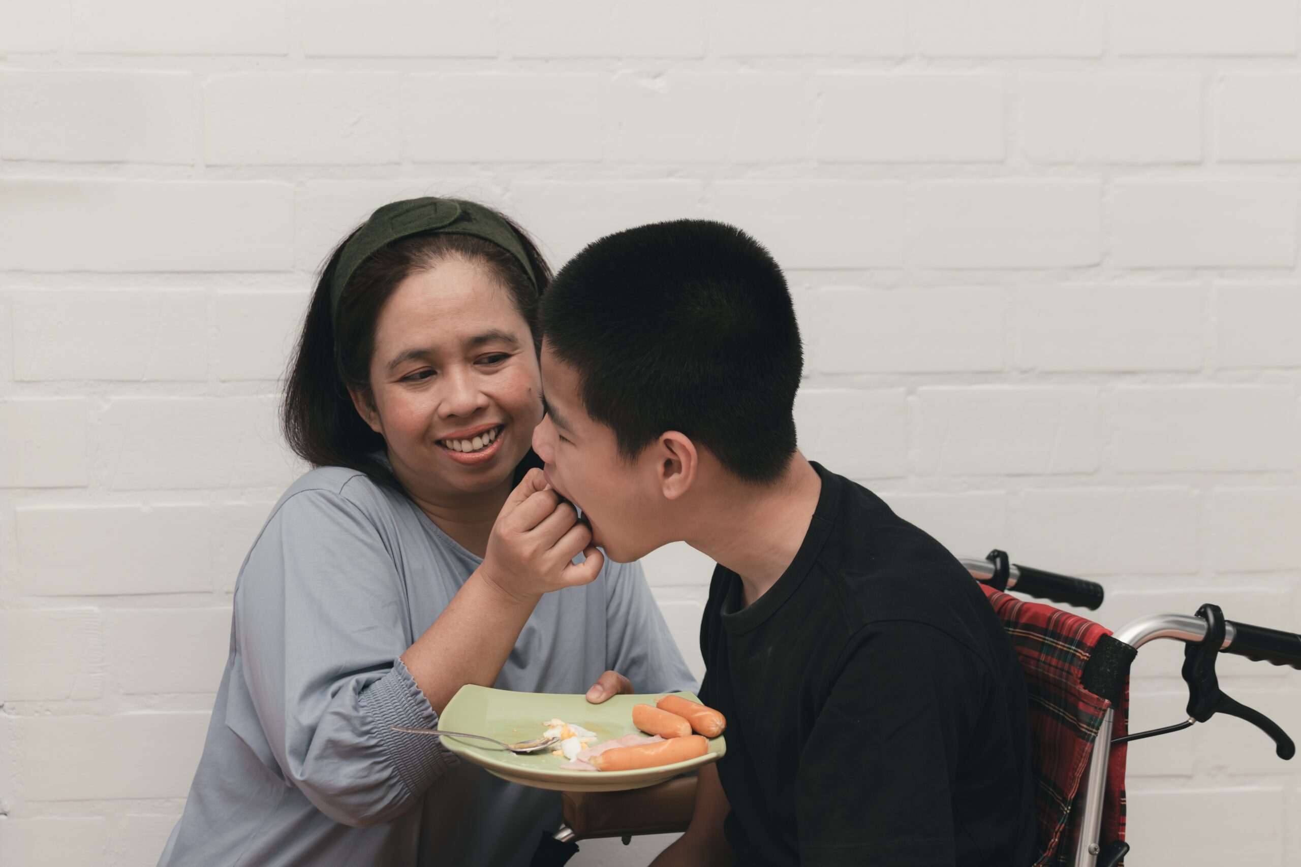 Support worker feeding person with disability – NDIS complex bowel care support tailored to participant needs and routines.