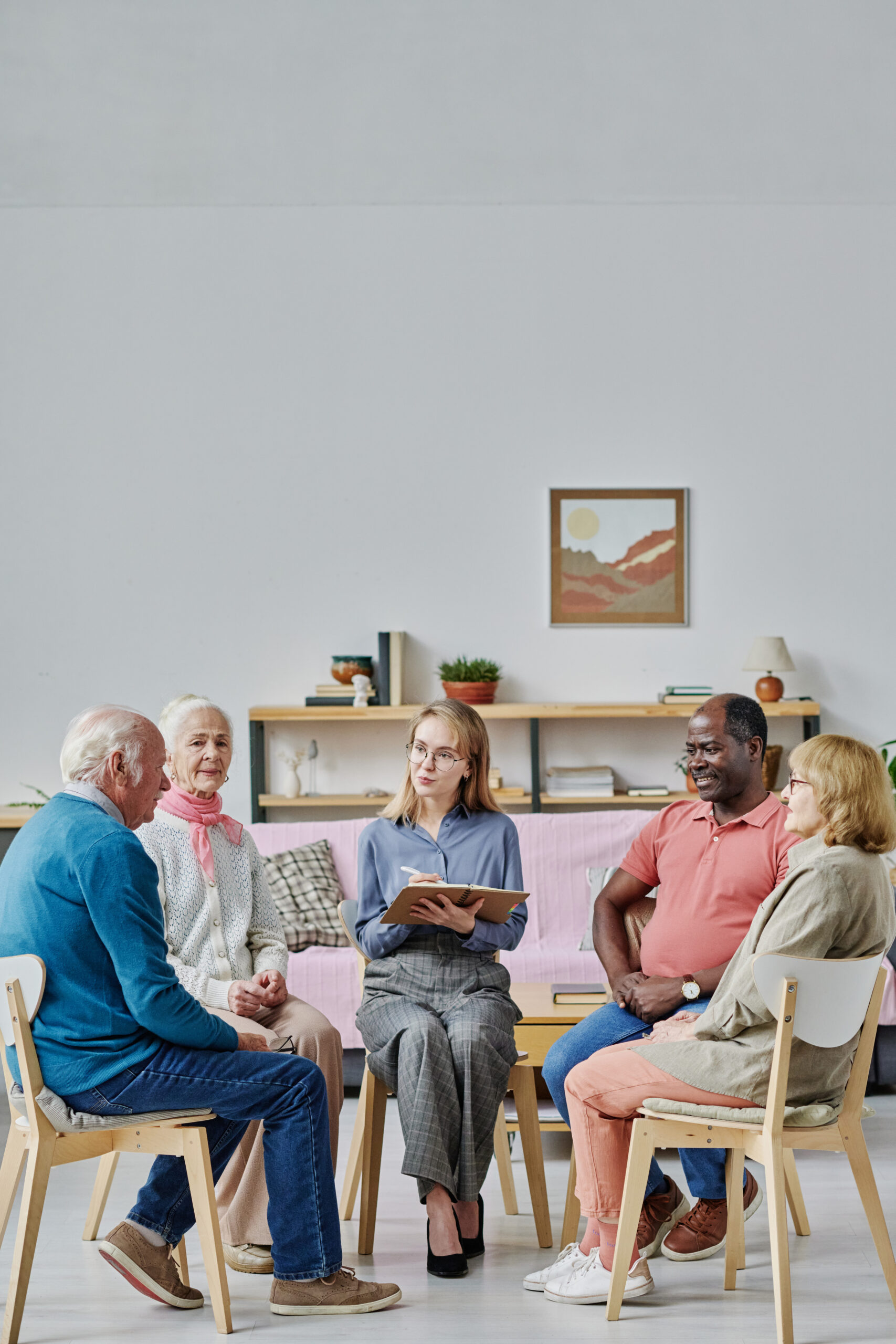 Group of NDIS participants receiving assistance with social and community participation, seated and engaged in discussion with a support coordinator.