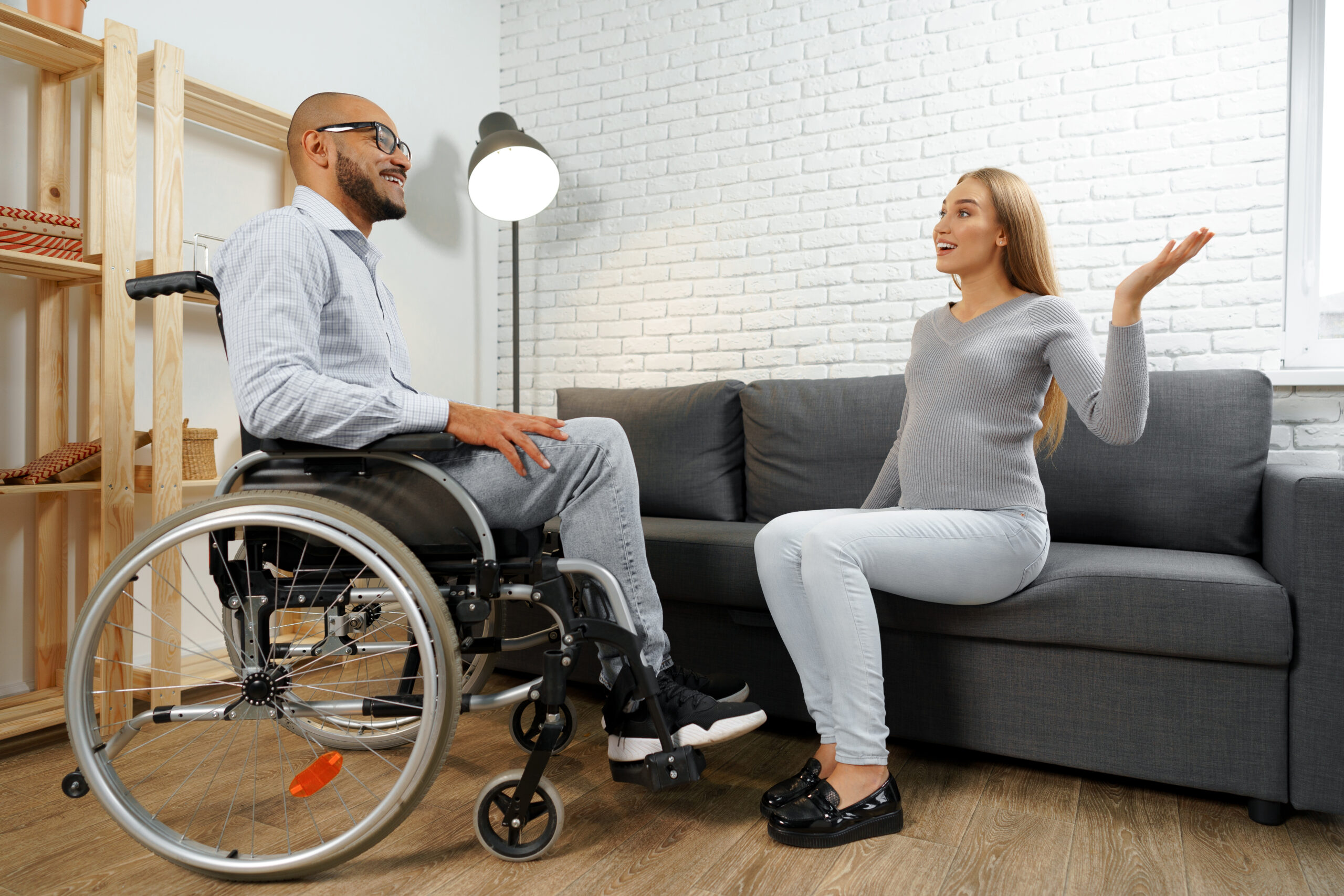 NDIS participant in a wheelchair talking with a support worker at home