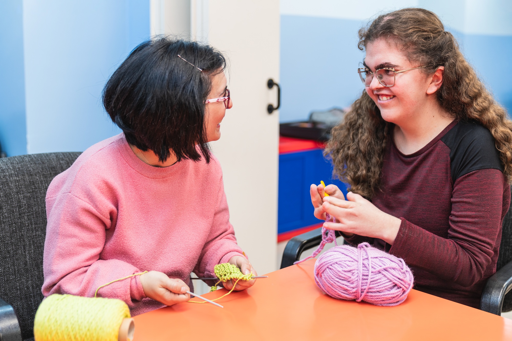 Support worker engaging in a craft activity with a young woman, illustrating compassionate community nursing interaction.