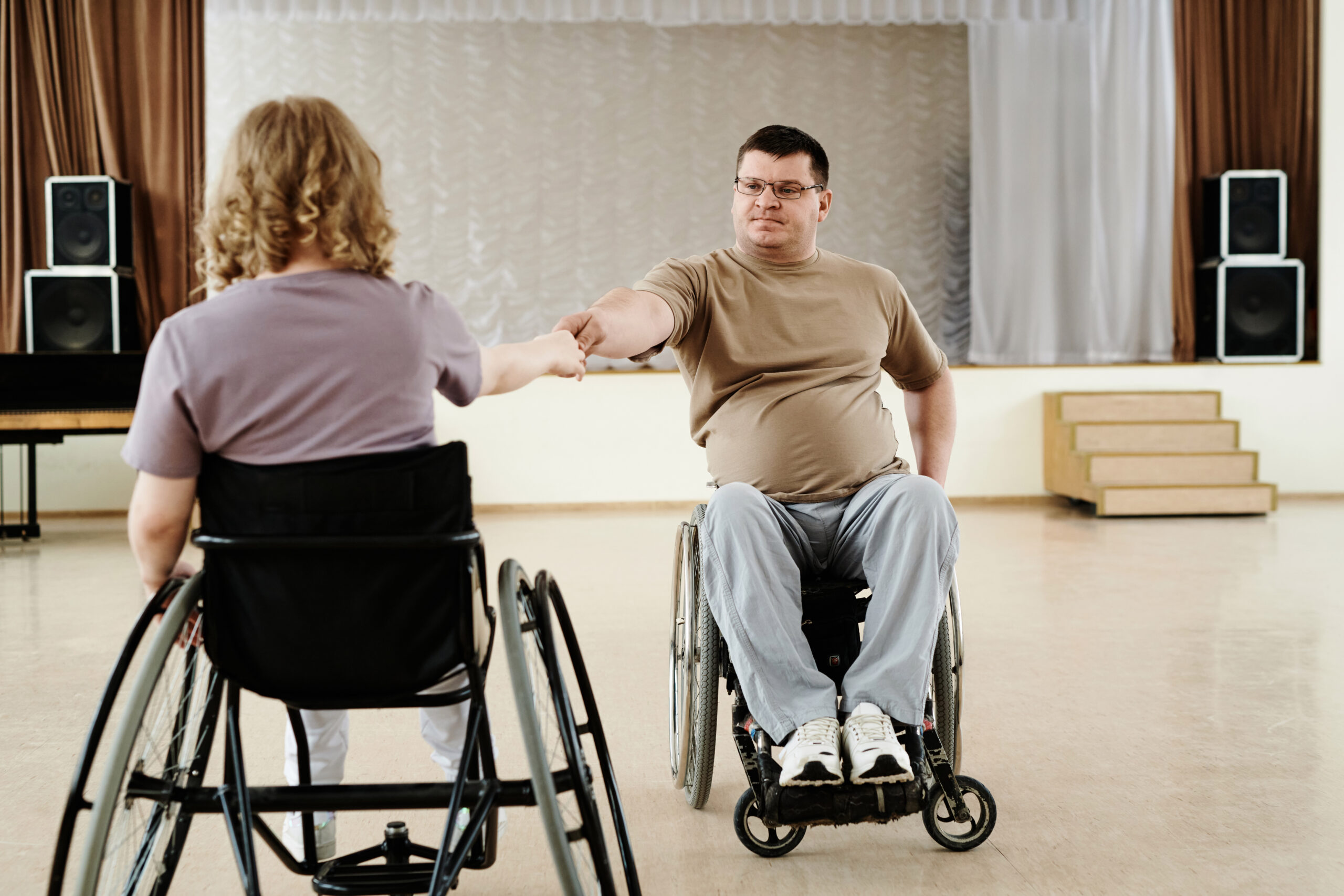 Two NDIS participants in wheelchairs supporting each other, symbolising daily tasks and shared independent living.