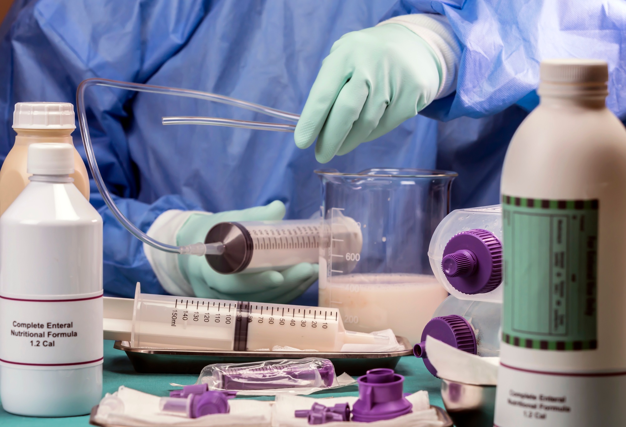 Nurse extracts enteral nutrition content with syringe